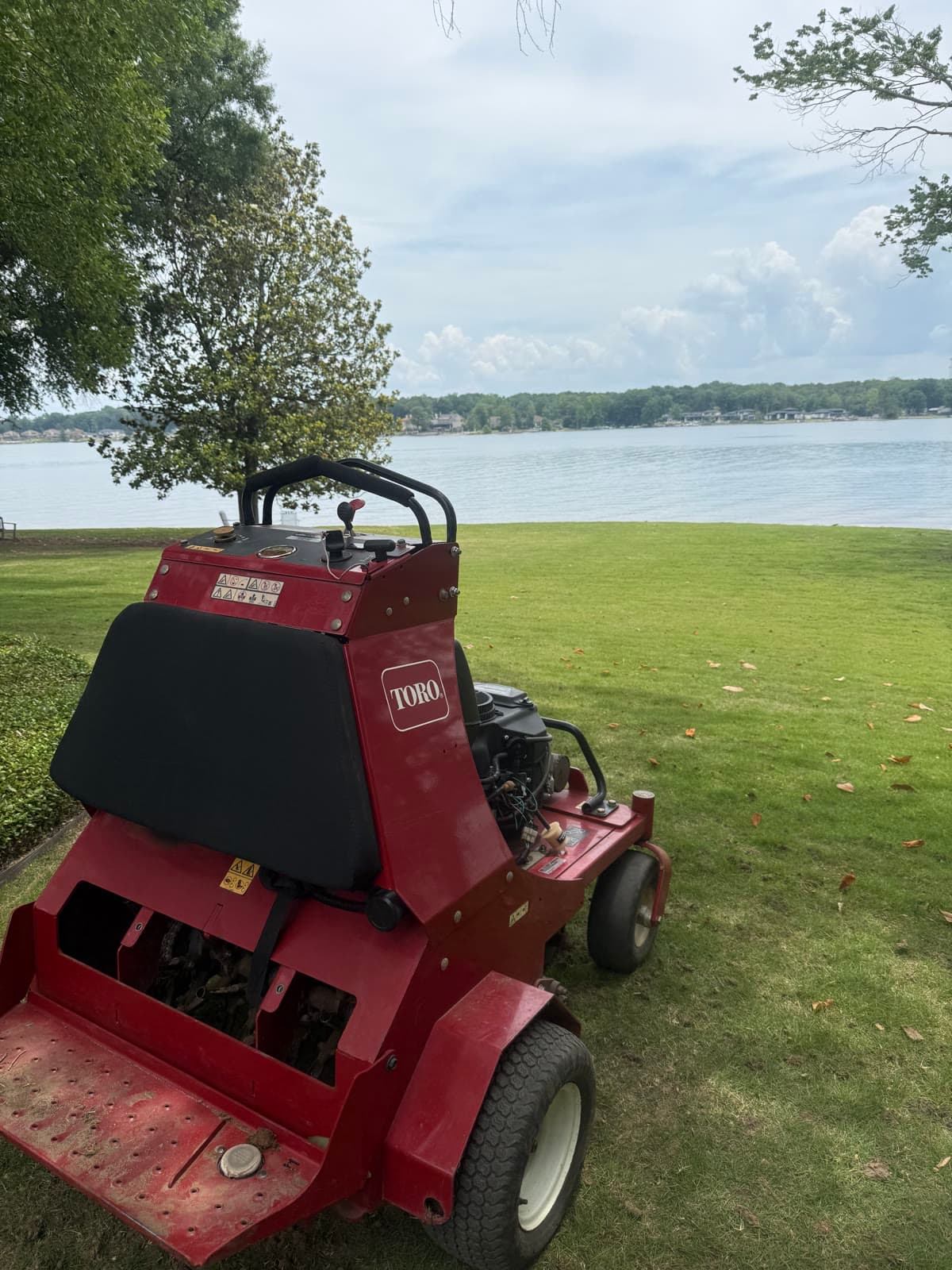 Ride-on core aerator pulling plugs from a lakeside lawn in Lexington, South Carolina